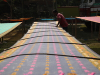 A weaver arranges a saree, a traditional cloth used for women's clothing, as it hangs out to dry after weaving it at a workshop in Santipur...