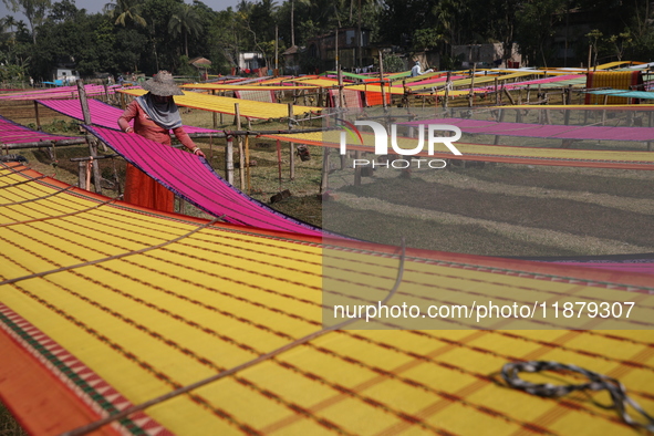 Weavers arrange sarees, a traditional cloth used for women's clothing, as they hang them out to dry after weaving at a workshop in Santipur...