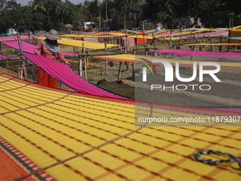 Weavers arrange sarees, a traditional cloth used for women's clothing, as they hang them out to dry after weaving at a workshop in Santipur...