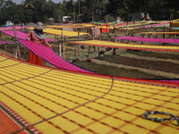 Weavers arrange sarees, a traditional cloth used for women's clothing, as they hang them out to dry after weaving at a workshop in Santipur...