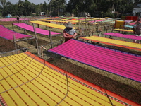 Weavers arrange sarees, a traditional cloth used for women's clothing, as they hang them out to dry after weaving at a workshop in Santipur...