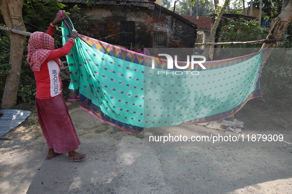 A weaver arranges a saree, a traditional cloth used for women's clothing, before hanging it out to dry after weaving it at a workshop in San...