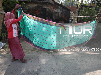 A weaver arranges a saree, a traditional cloth used for women's clothing, before hanging it out to dry after weaving it at a workshop in San...