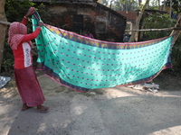 A weaver arranges a saree, a traditional cloth used for women's clothing, before hanging it out to dry after weaving it at a workshop in San...