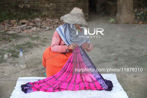 Weavers arrange sarees, a traditional cloth used for women's clothing, as they hang them out to dry after weaving at a workshop in Santipur...