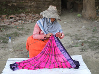 Weavers arrange sarees, a traditional cloth used for women's clothing, as they hang them out to dry after weaving at a workshop in Santipur...