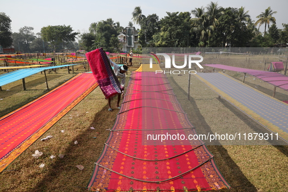 Weavers arrange sarees, a traditional cloth used for women's clothing, as they hang them out to dry after weaving at a workshop in Santipur...