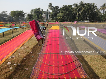 Weavers arrange sarees, a traditional cloth used for women's clothing, as they hang them out to dry after weaving at a workshop in Santipur...