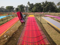 Weavers arrange sarees, a traditional cloth used for women's clothing, as they hang them out to dry after weaving at a workshop in Santipur...