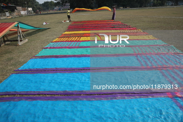 Weavers arrange sarees, a traditional cloth used for women's clothing, as they hang them out to dry after weaving at a workshop in Santipur...