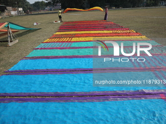 Weavers arrange sarees, a traditional cloth used for women's clothing, as they hang them out to dry after weaving at a workshop in Santipur...