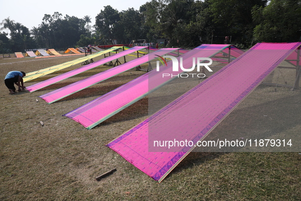 A weaver arranges sarees, a traditional cloth used for women's clothing, as they hang out to dry after weaving at a workshop in Santipur tow...