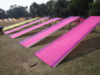 A weaver arranges sarees, a traditional cloth used for women's clothing, as they hang out to dry after weaving at a workshop in Santipur tow...