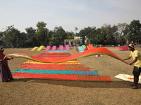 Weavers arrange sarees, a traditional cloth used for women's clothing, as they hang them out to dry after weaving at a workshop in Santipur...