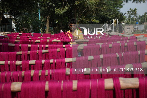 A weaver dries threads before weaving a saree, a traditional cloth used for women's clothing, at a workshop in Santipur town, about 80 km fr...