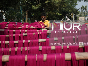 A weaver dries threads before weaving a saree, a traditional cloth used for women's clothing, at a workshop in Santipur town, about 80 km fr...