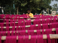 A weaver dries threads before weaving a saree, a traditional cloth used for women's clothing, at a workshop in Santipur town, about 80 km fr...