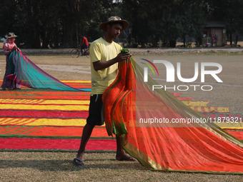 Weavers arrange sarees, a traditional cloth used for women's clothing, after weaving them at a workshop in Santipur town, about 80 km from K...