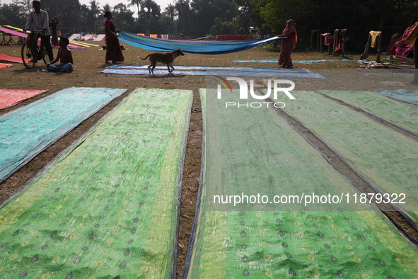 Weavers arrange sarees, a traditional cloth used for women's clothing, as they hang them out to dry after weaving at a workshop in Santipur...