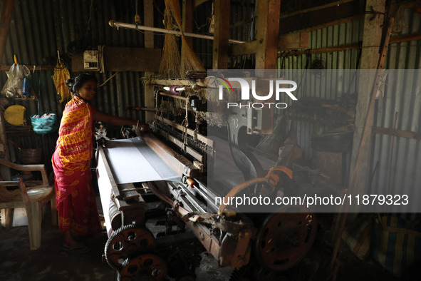 A weaver makes a saree, a traditional cloth used for women's clothing, on a power loom at a workshop in Santipur town, about 80 km from Kolk...