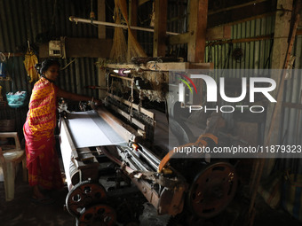 A weaver makes a saree, a traditional cloth used for women's clothing, on a power loom at a workshop in Santipur town, about 80 km from Kolk...