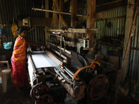 A weaver makes a saree, a traditional cloth used for women's clothing, on a power loom at a workshop in Santipur town, about 80 km from Kolk...