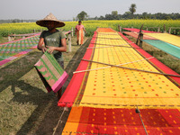 A weaver arranges a saree, a traditional cloth used for women's clothing, as it hangs out to dry after weaving it at a workshop in Santipur...