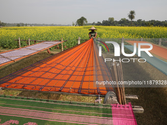 A weaver arranges a saree, a traditional cloth used for women's clothing, as it hangs out to dry after weaving it at a workshop in Santipur...