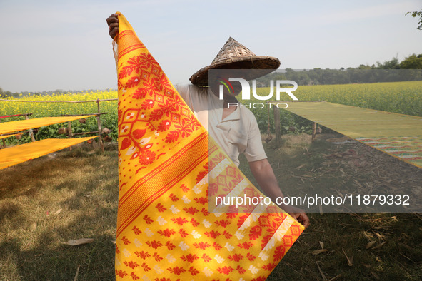 A weaver arranges a saree, a traditional cloth used for women's clothing, as it hangs out to dry after weaving it at a workshop in Santipur...