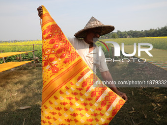 A weaver arranges a saree, a traditional cloth used for women's clothing, as it hangs out to dry after weaving it at a workshop in Santipur...