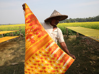 A weaver arranges a saree, a traditional cloth used for women's clothing, as it hangs out to dry after weaving it at a workshop in Santipur...