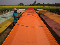 A weaver arranges a saree, a traditional cloth used for women's clothing, as it hangs out to dry after weaving it at a workshop in Santipur...