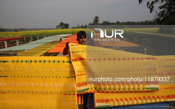 A weaver arranges a saree, a traditional cloth used for women's clothing, as it hangs out to dry after weaving it at a workshop in Santipur...