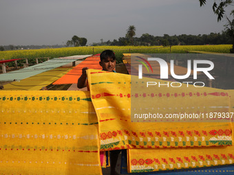 A weaver arranges a saree, a traditional cloth used for women's clothing, as it hangs out to dry after weaving it at a workshop in Santipur...