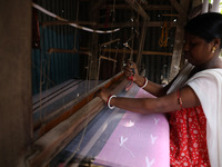 A weaver makes a saree, a traditional cloth used for women's clothing, on a hand loom at a workshop in Santipur town, about 80 km from Kolka...