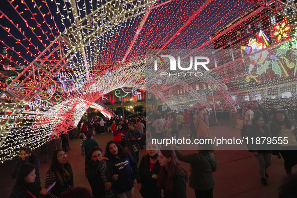 People walk under a light dome during the opening of the 2024 Christmas Festival at the Zocalo in Mexico City, Mexico, on December 18, 2024....