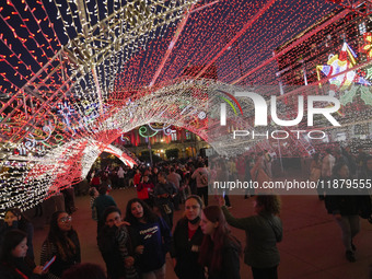 People walk under a light dome during the opening of the 2024 Christmas Festival at the Zocalo in Mexico City, Mexico, on December 18, 2024....