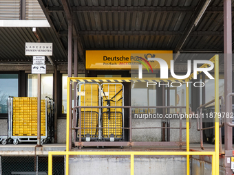 A Deutsche Post loading area in Munich, Germany, on December 18, 2024, contains yellow postal containers and trolleys positioned in the load...