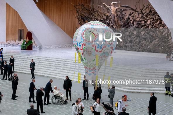 Pope Francis examines an air balloon presented to him at the end of the weekly general audience in The Vatican, on December 18, 2024, at Pau...