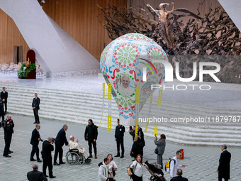 Pope Francis examines an air balloon presented to him at the end of the weekly general audience in The Vatican, on December 18, 2024, at Pau...