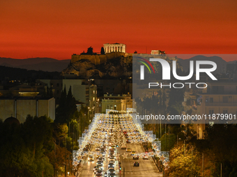 Christmas lights decorate a main street with the Acropolis in the background in Athens, Greece, on December 18, 2024. (