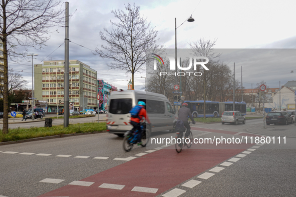 Cyclists, cars, and a bus are at an intersection in Munich, Bavaria, Germany, on December 18, 2024 