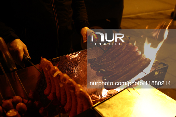 A person prepares sausages traditionally served at blue Nyska van in Krakow, Poland on December 18, 2024. 