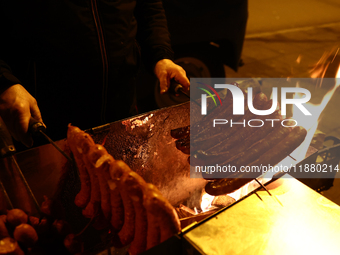 A person prepares sausages traditionally served at blue Nyska van in Krakow, Poland on December 18, 2024. (