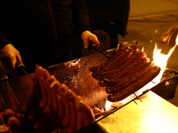 A person prepares sausages traditionally served at blue Nyska van in Krakow, Poland on December 18, 2024. (