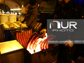 A person prepares sausages traditionally served at blue Nyska van in Krakow, Poland on December 18, 2024. (