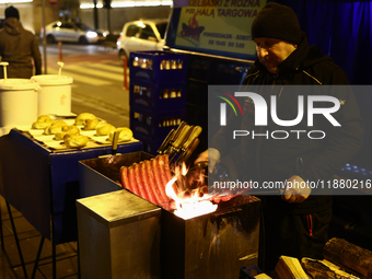 A person prepares sausages traditionally served at blue Nyska van in Krakow, Poland on December 18, 2024. (