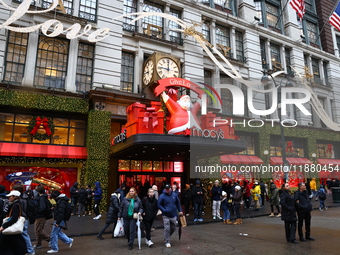 People stand outside Macy's Department Store windows in New York, N.Y., on December 17, 2024. (