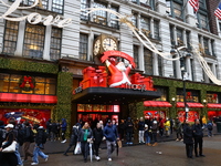 People stand outside Macy's Department Store windows in New York, N.Y., on December 17, 2024. (