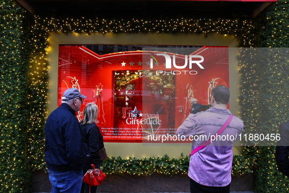 People take photos with their mobile devices of Macy's department store windows in New York, N.Y., on December 17, 2024. 